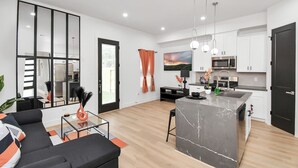 Una cocina moderna con una isla central, armarios blancos y un amplio ventanal.