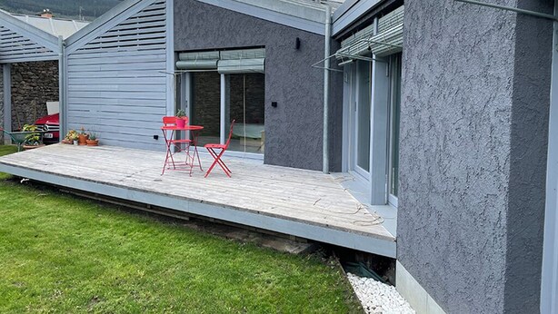 A modern house with a flat roof, a covered patio with red chairs, and a stone wall. - Osteiko Etxea. Entire apartment. Sleeps 5. (Orozko)