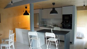 A modern kitchen with white bar stools, a central island, and pendant lighting. - Osteiko Etxea. Entire apartment. Sleeps 5. (Orozko)