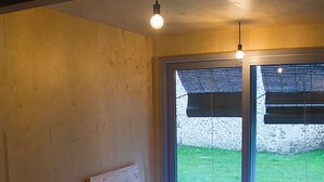 A bedroom with two beds, a nightstand, a lamp, and a window with blinds. - Osteiko Etxea. Entire apartment. Sleeps 5. (Orozko)
