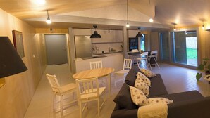 A modern living room with a sofa, chairs, a dining table, and a kitchen area with a refrigerator and stove. - Osteiko Etxea. Entire apartment. Sleeps 5. (Orozko)