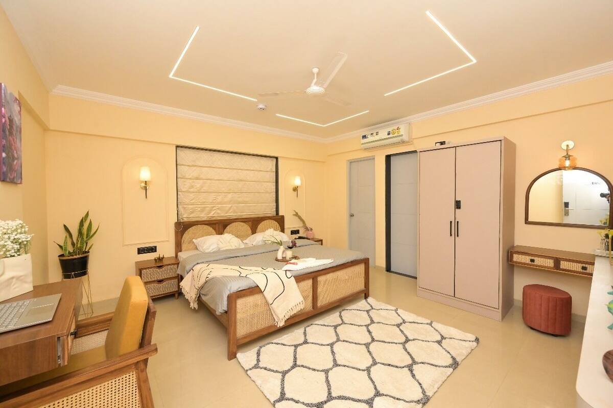 A bedroom with a bed, bedside tables, a desk, a wardrobe, and a bathroom.