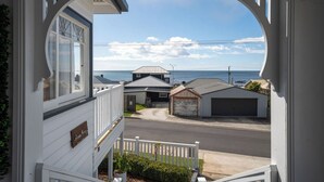 A coastal residential area with a view through a white-framed window. - Ocean Breeze - Modern Comfort with Outdoor Entertaining and Ocean Views (Parklands)