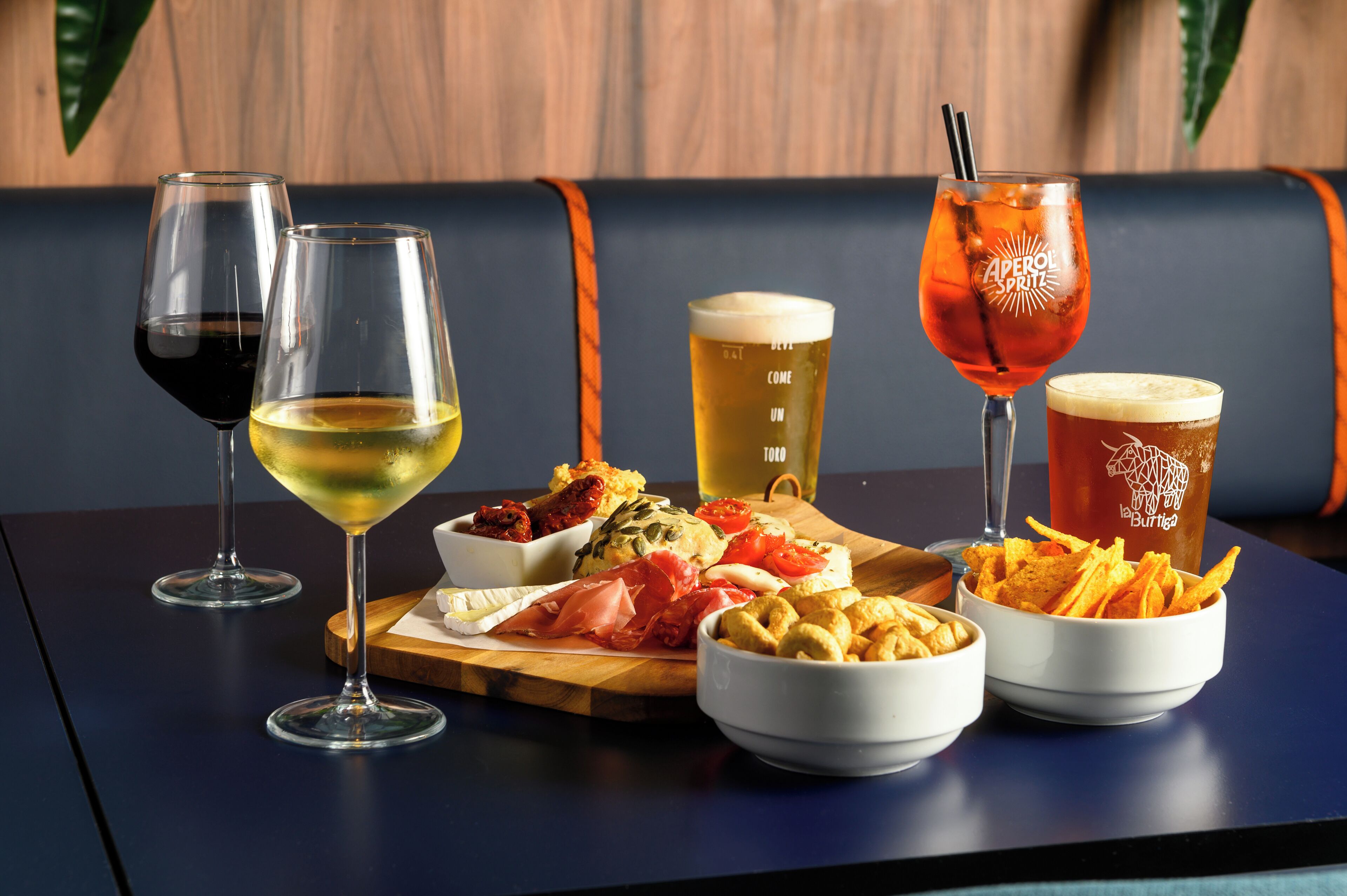 A table with various drinks and food items, including wine glasses, a beer mug, and bowls of snacks.