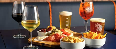 A table with various drinks and food items, including wine glasses, a beer mug, and bowls of snacks.