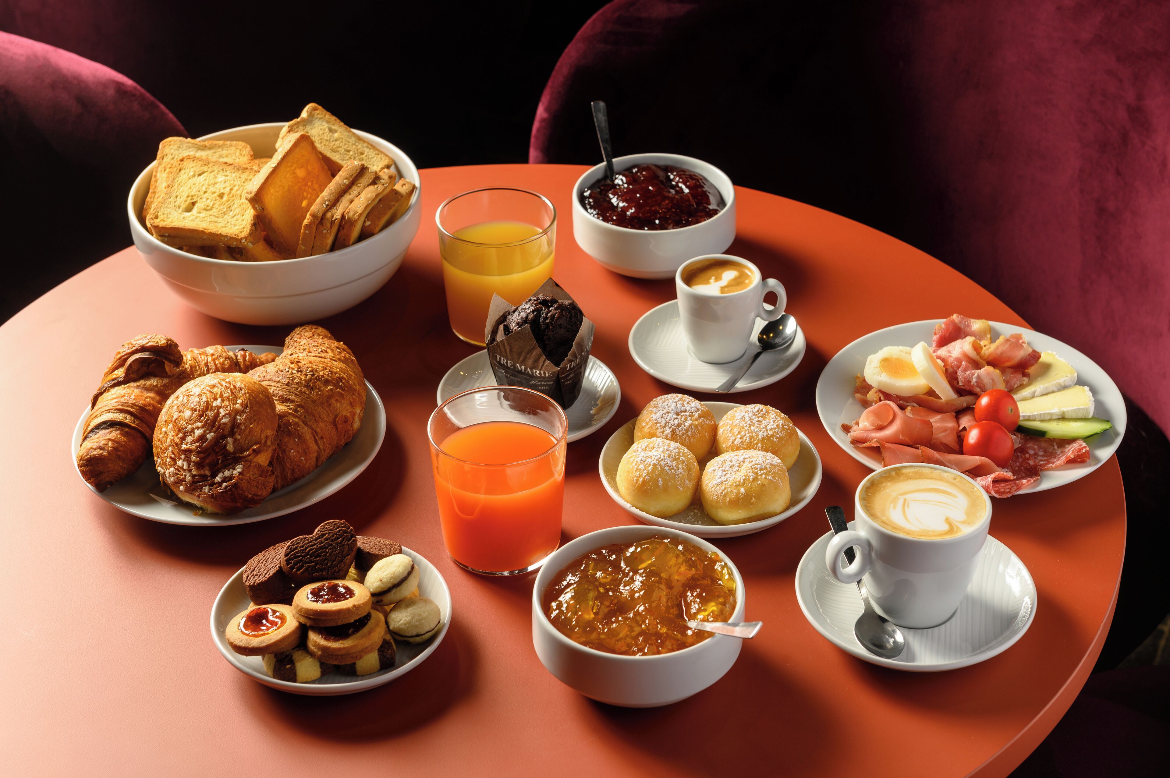 A table with breakfast items including croissants, muffins, and a coffee cup.