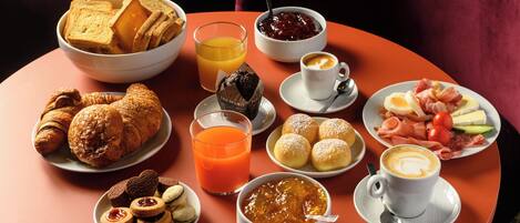 A table with breakfast items including croissants, muffins, and a coffee cup.