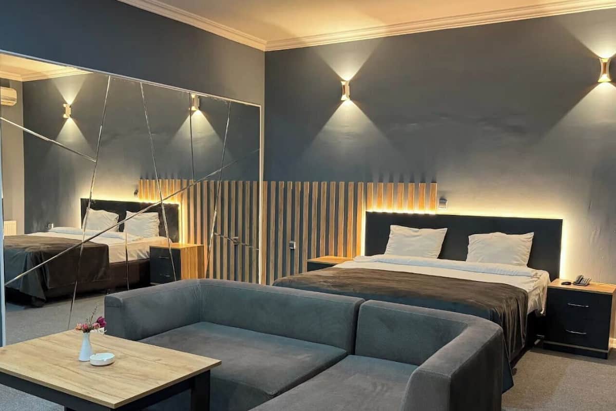 Une chambre d’hôtel moderne avec un grand lit, un canapé, une petite table et un miroir.