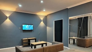 Ein modernes Zimmer mit einem Flachbildfernseher an der Wand, einer Couch, einem kleinen Tisch und einem Spiegel.