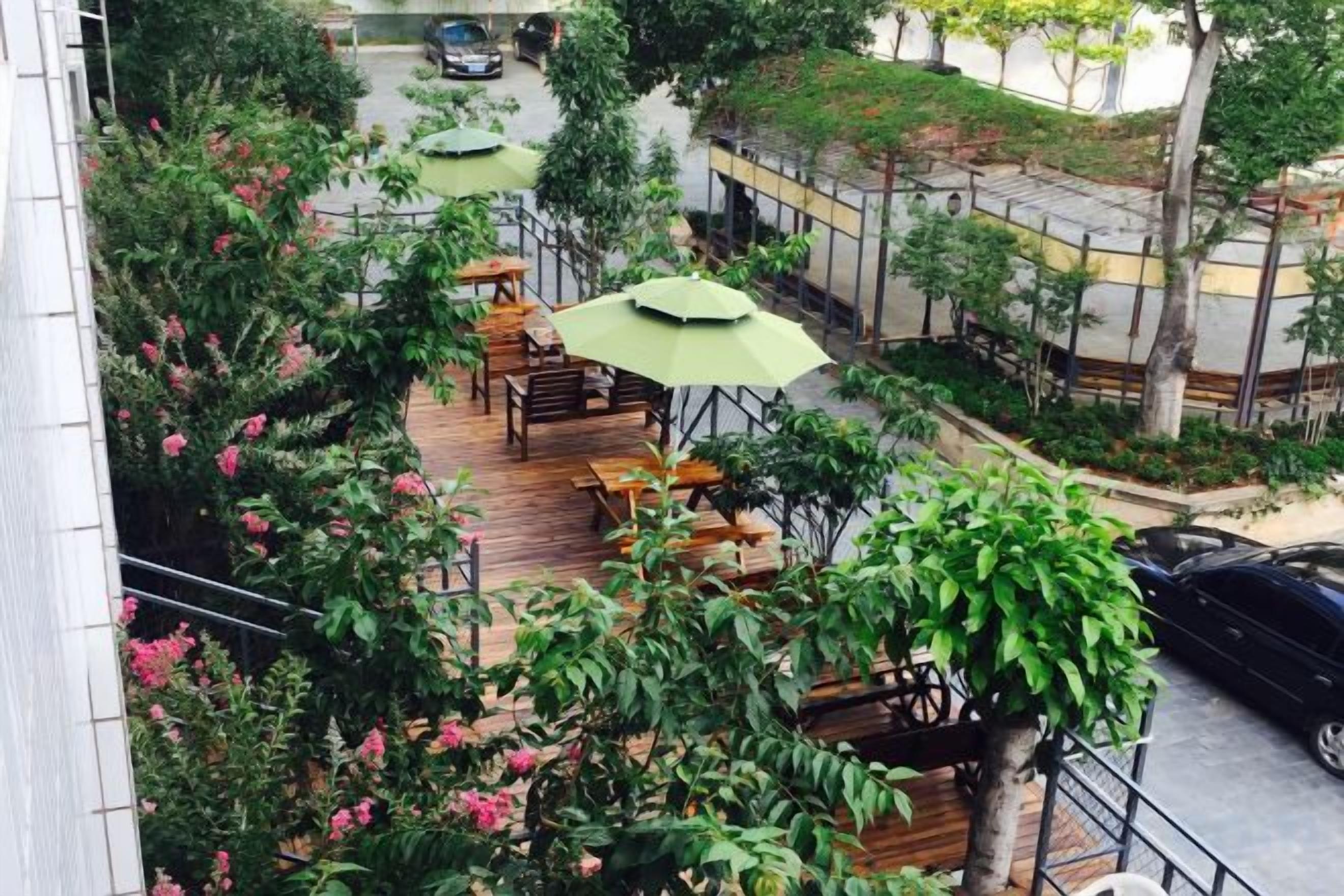 An outdoor seating area with tables and chairs, surrounded by greenery and trees.