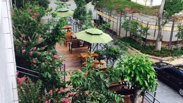 An outdoor seating area with tables and chairs, surrounded by greenery and trees.
