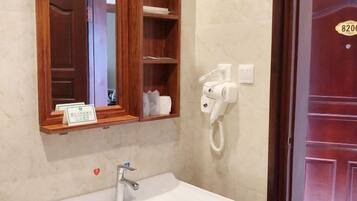 A bathroom with a sink, mirror, and a hairdryer on the wall.