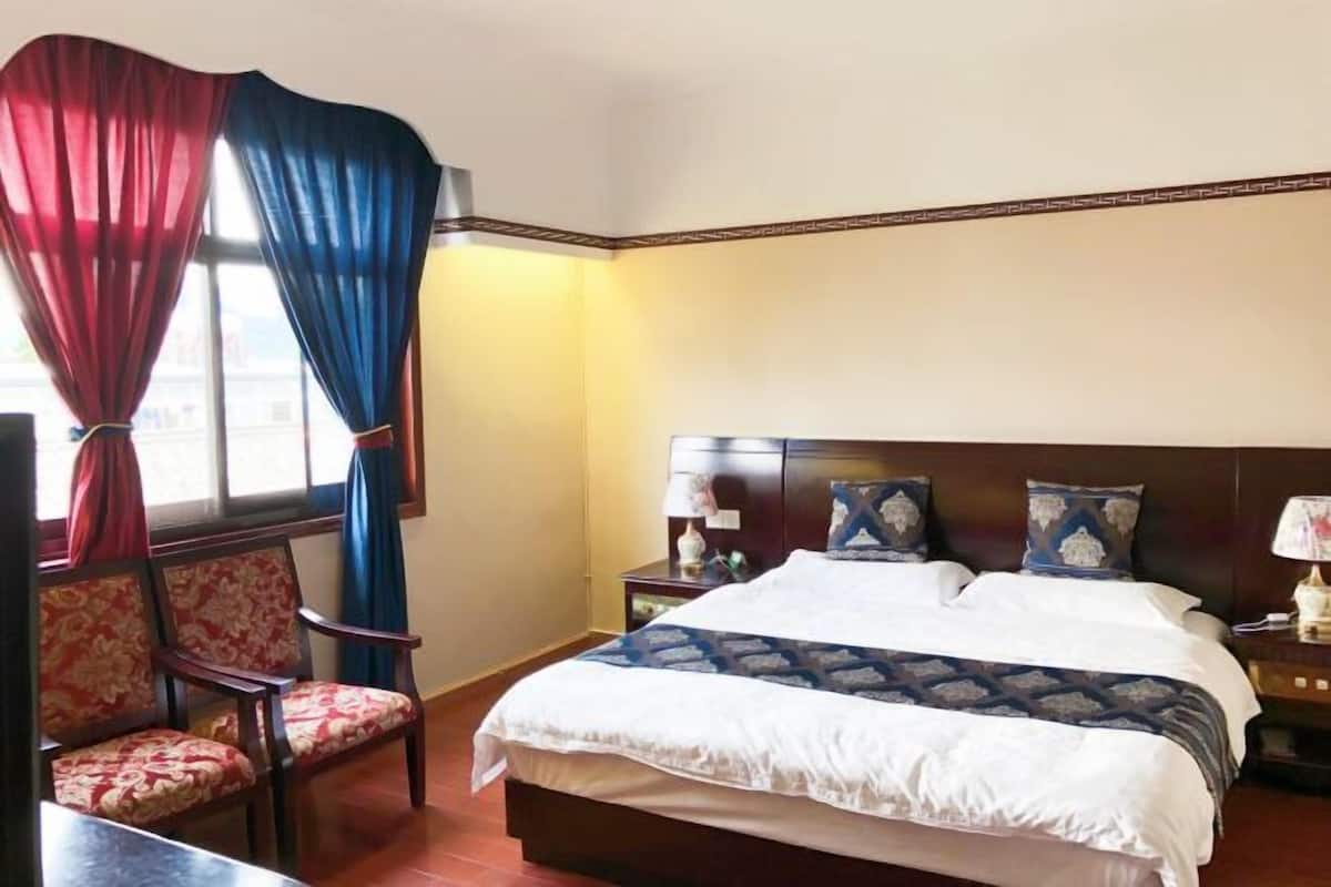 A hotel room with a bed, two nightstands, a chair, and a window with curtains.