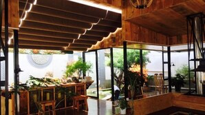 A spacious interior with a wooden ceiling, large windows, and a variety of seating arrangements. - New Hotel Busan (Weishan)