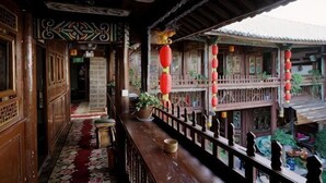 A traditional wooden balcony with a railing, potted plants, and red lanterns. - New Hotel Busan (Weishan)