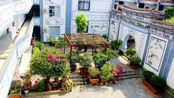 Un patio con plantas en macetas, una pérgola de madera y paredes con azulejos blancos y azules tradicionales.
