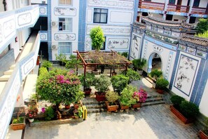 A courtyard with potted plants, a wooden pergola, and traditional blue and white tiled walls. - New Hotel Busan (Weishan)
