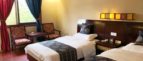 A hotel room with two beds, a chair, a nightstand, and a window with curtains.