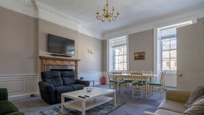 En stue med pejs, fjernsyn, spiseplads med stole og en sofa.