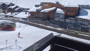 En snötäckt bergsby med en skidort, inklusive byggnader med skidliftar och en klarblå himmel.