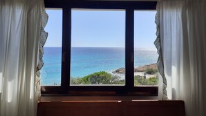 A room with a large window overlooking a beach and the sea. - Beachfront house with breathtaking views  (Pula)