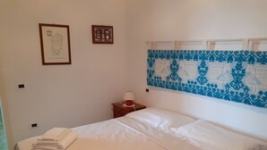 A neatly made bed with white linens and a folded towel on the side. There is a small bedside table with a lamp and a framed picture on the wall above it. - Beachfront house with breathtaking views  (Pula)