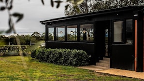 Un edificio moderno de color negro con ventanas amplias y un césped bien cuidado.