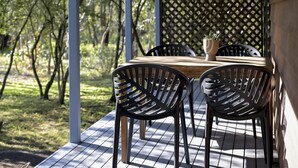 Una terraza de madera con una mesa y sillas, rodeada por una valla de madera y árboles.