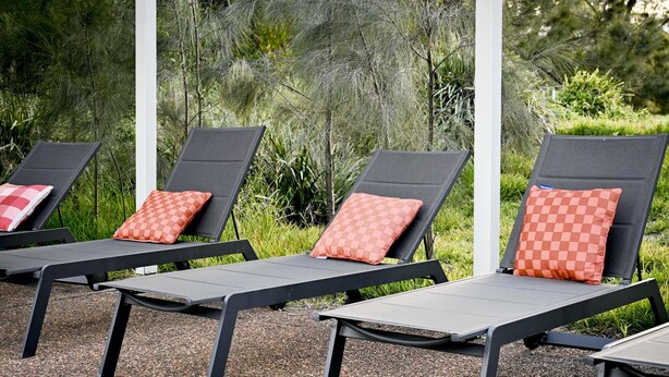 Three lounge chairs with checkered cushions, arranged outdoors with a gravel ground and greenery in the background. - Twin Tree Bush Cabin in the Heart of the Hunter Valley! 
1 of 10 Cabins listed! (Pokolbin)