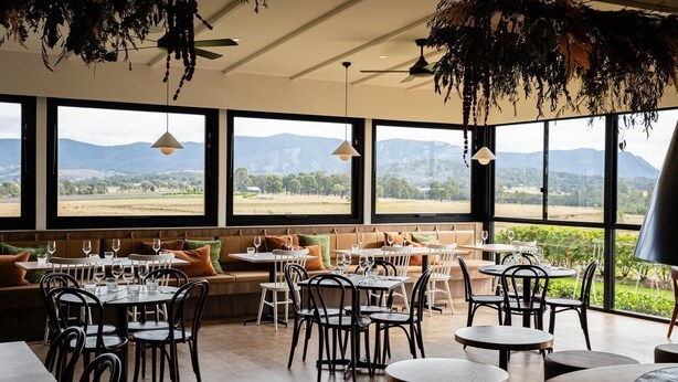 A restaurant with large windows offering a view of the countryside. Tables and chairs are arranged for dining. - Cedar Cabin 1 - 2 bedroom with 1 x queen and 1 King or 2 king singles + sofa bed (Pokolbin)
