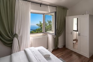 A bedroom with a bed, a window with a view, a wardrobe, and a radiator. -  Casa Giuseppe (Labin)