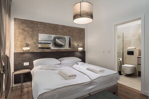 A modern hotel room with a large bed, bedside tables, a painting on the wall, and a bathroom visible through an open door. -  Casa Giuseppe (Labin)