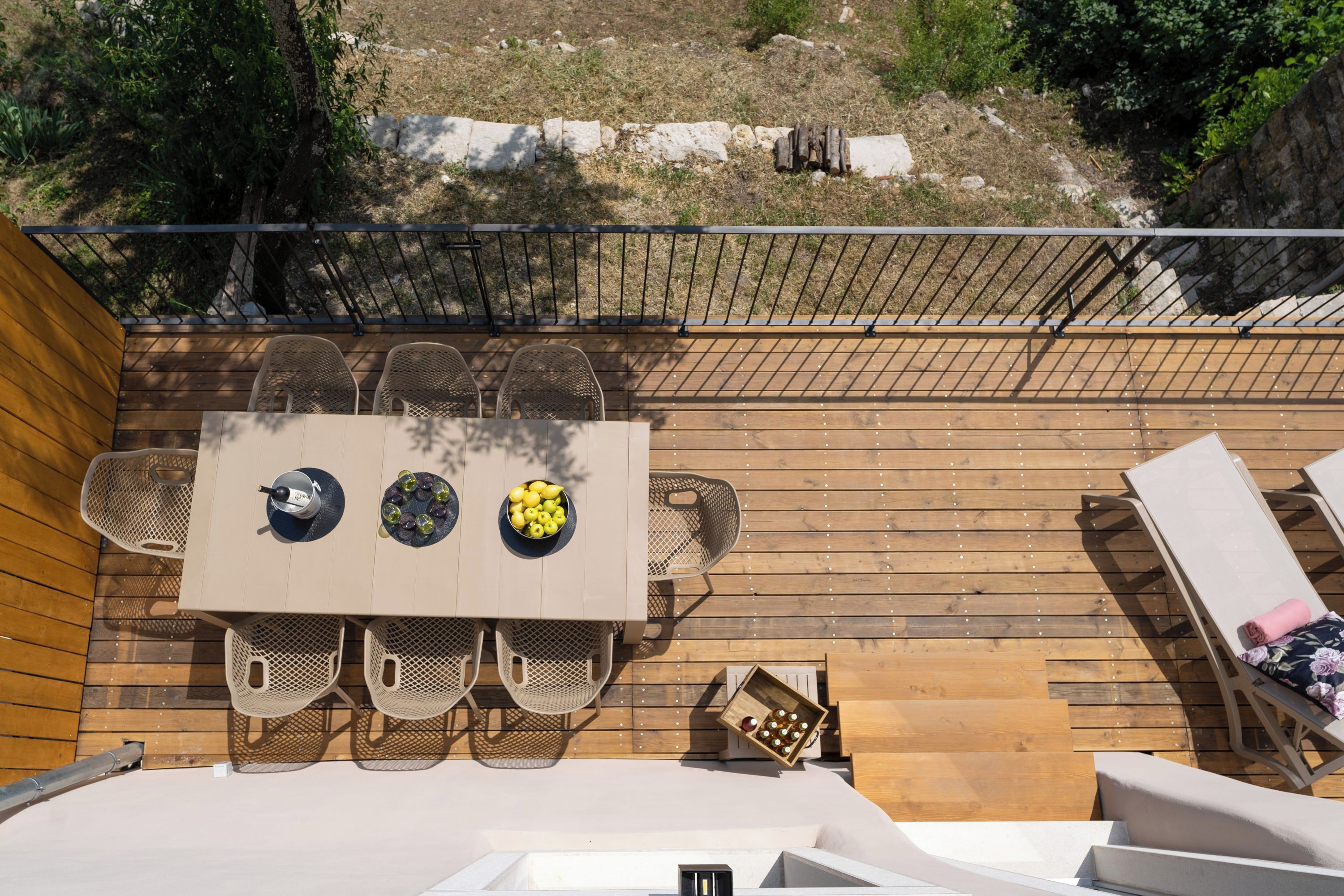 An outdoor wooden deck with a table and chairs, a small box of chocolates, and a railing.