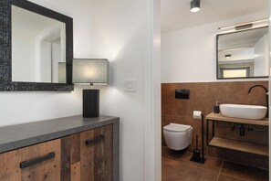 A modern bathroom with a large mirror, a sink, and a toilet. -  Casa Giuseppe (Labin)