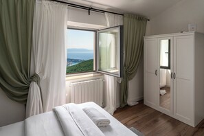 A bedroom with a bed, a wardrobe, and a window with curtains. - Casa Giuseppe (Labin)