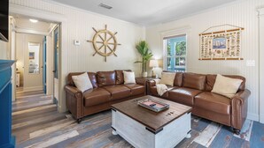 Ein Wohnzimmer mit einem braunen Ledersofa, einem Holztisch und einer Wanddekoration im Stil eines Schiffsschwenders.