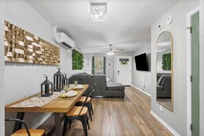 Zona pranzo moderna con tavolo in legno, sedie e ventilatore a soffitto.