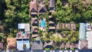 Vista aérea de una zona residencial con varias casas, una piscina y abundante vegetación.