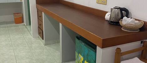 Una cocina con encimera de madera, una tetera, una cesta y un cubo de basura.