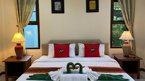 Habitación de hotel con una cama grande, dos mesitas de noche, dos lámparas, una ventana con cortinas y dos cuadros enmarcados en la pared.