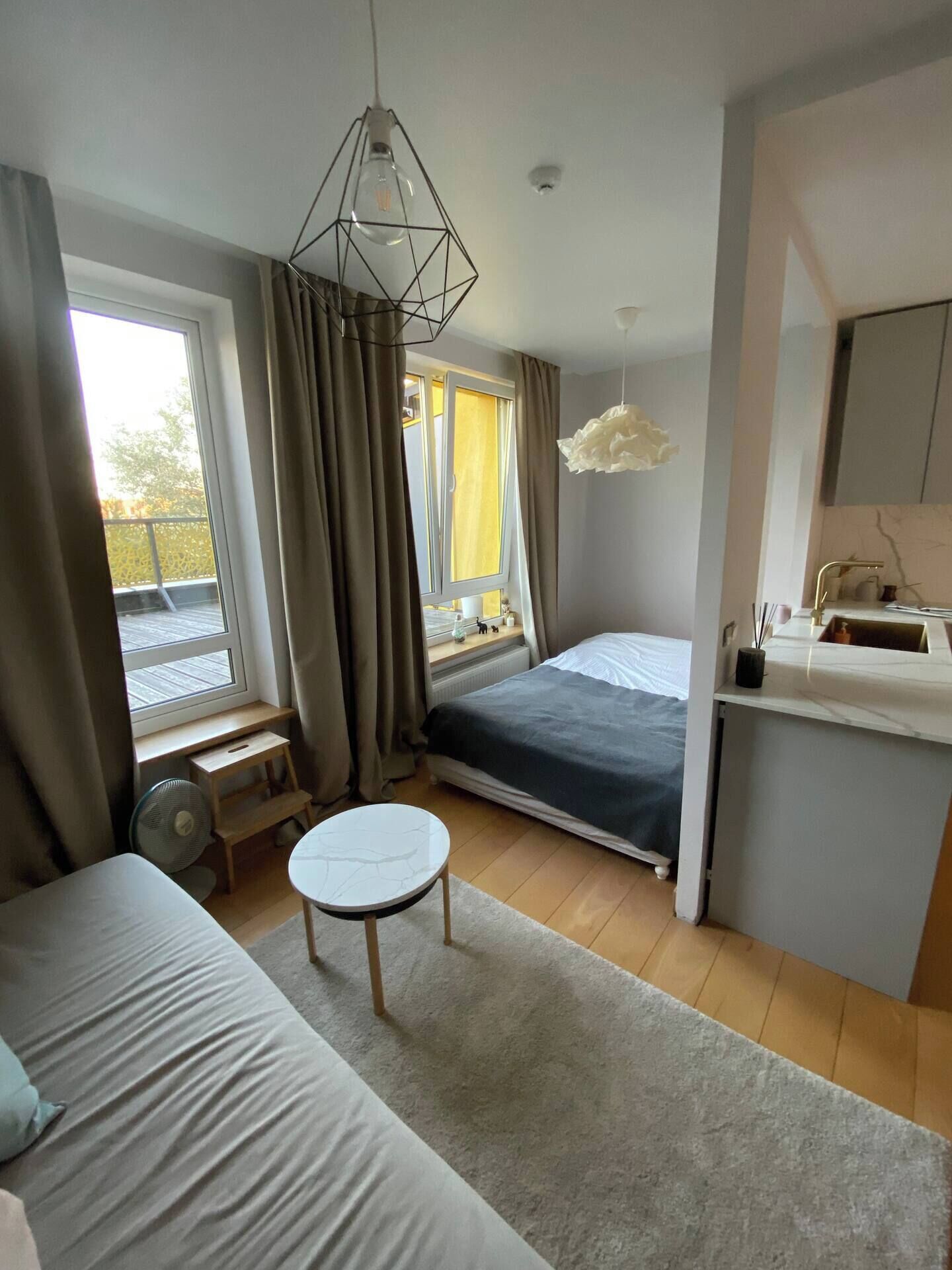 A modern bedroom with a bed, bedside table, and a view of the outdoors.