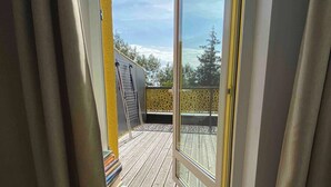 A view from a window to a wooden deck with a metal ladder and a stack of books.
