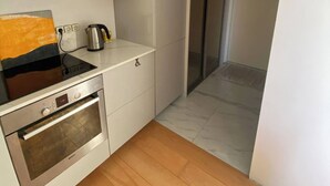 A modern kitchen with white cabinets, a built-in oven, and a coffee maker.