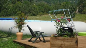 A wooden deck with a lounge chair, a metal chair, and a potted plant. - Roulotte Cévenole (Aulas)