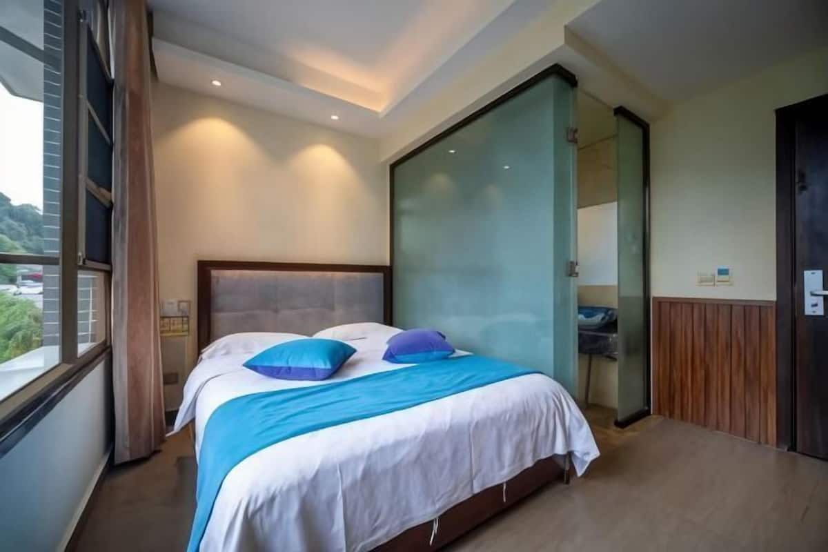 A bedroom with a bed, a window, a sliding door, and a view of the outside.