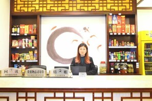 A reception desk with a woman behind it, surrounded by shelves of products.