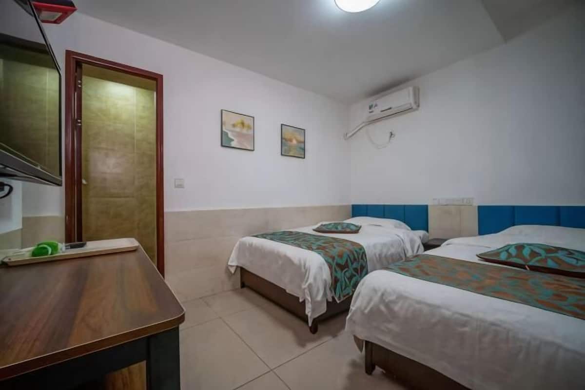 A bedroom with two beds, a desk, and a door.