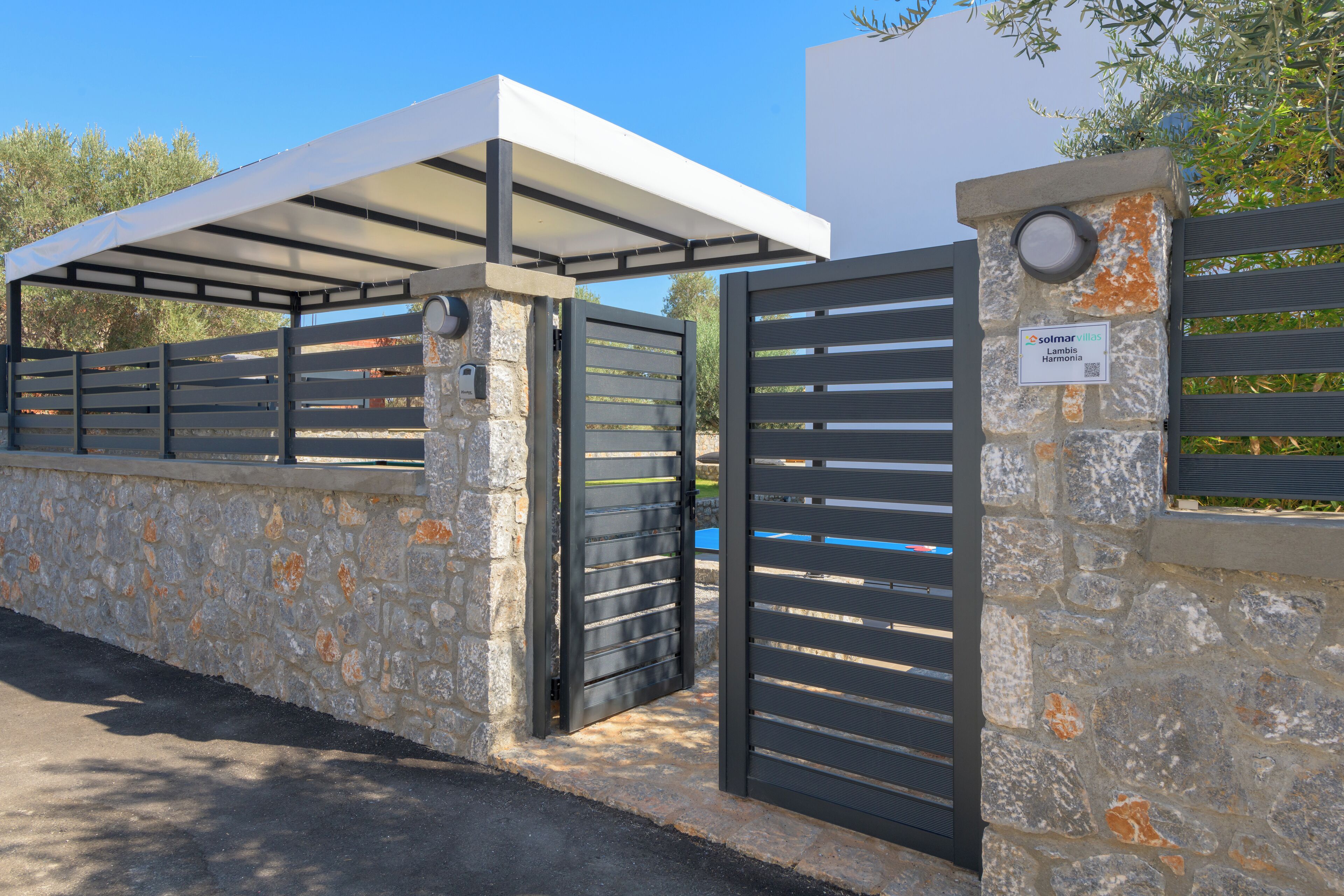A gated entrance with a stone wall and a metal gate.