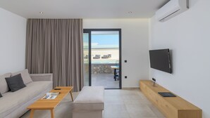 Una sala de estar moderna con un sofá, una mesa de centro, un televisor y vistas a un balcón con piscina.