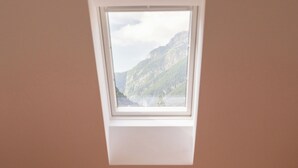 A bedroom with a bed, a window, and a view of mountains.